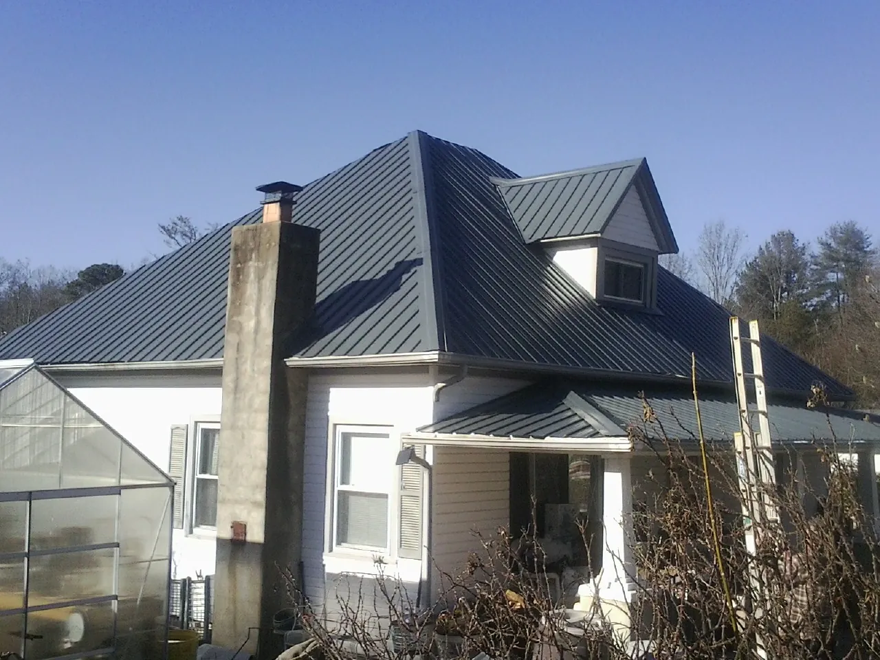 Dark blue standing seam metal roof on a white farmhouse with dormer — Slate & Tile Roof Repair by Roofing Brothers in Ola