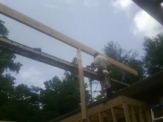 Carpenter setting a ridge beam over a new addition frame — Ice Dam Removal by Roofing Brothers in Ola