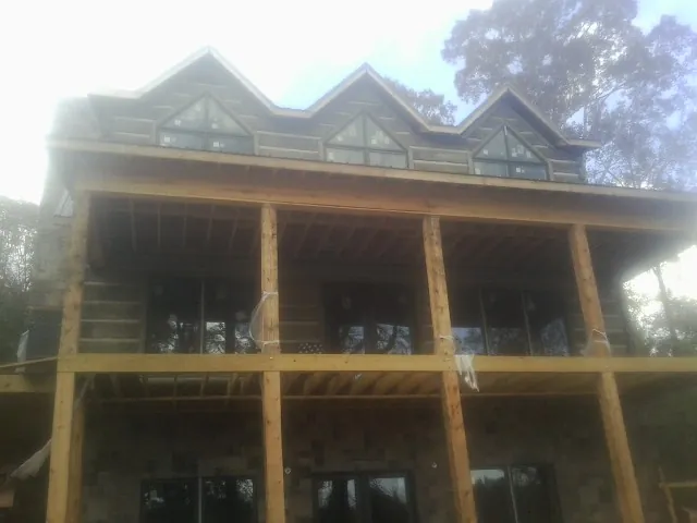 Dormers and porch framing on a large log home under construction — Roof Coating work by our crew in Ola